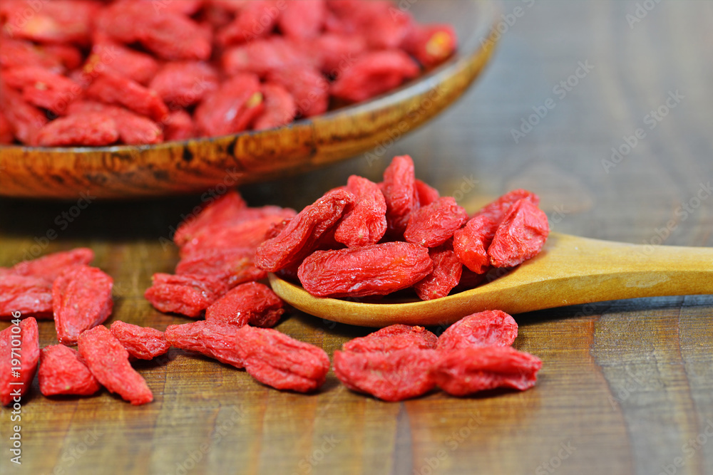 Dried goji berries in wooden spoon and plate (Lycium chinense) macro selective focus Dried goji berries in wooden spoon and plate (Lycium chinense) macro selective focus