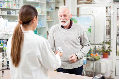 Medicine, pharmaceutics, health care and people concept - Happy senior male customer paying for medications at a drugstore