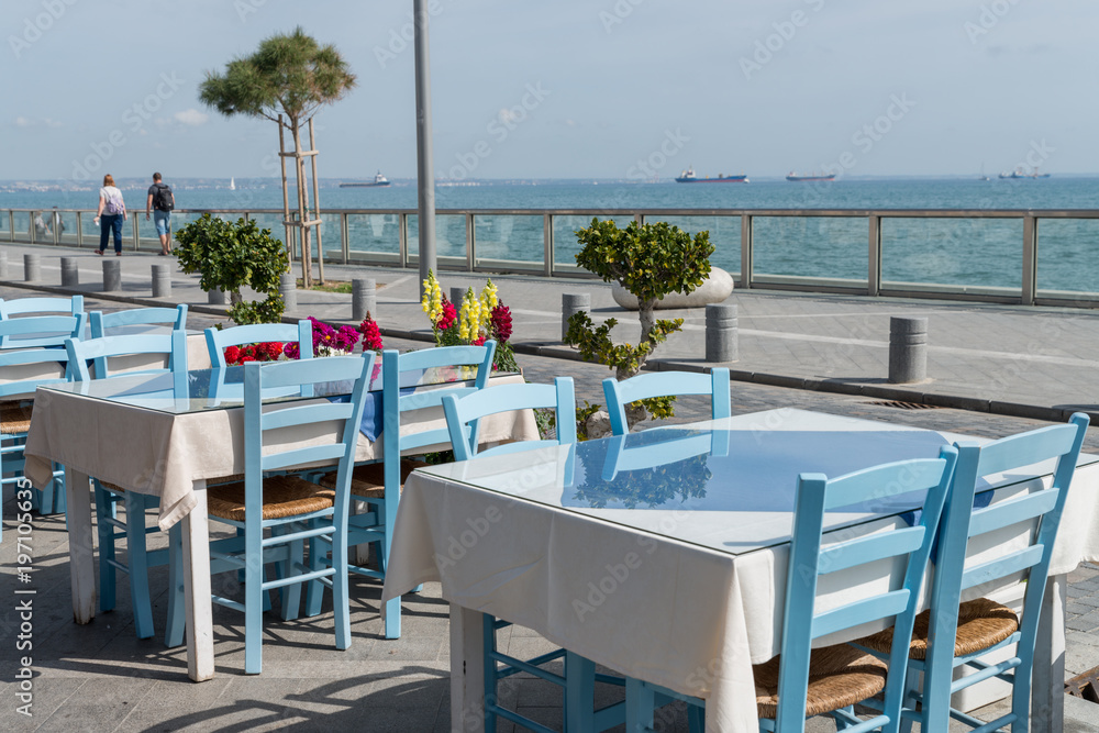 Several empty tables with chairs on the sea embankment