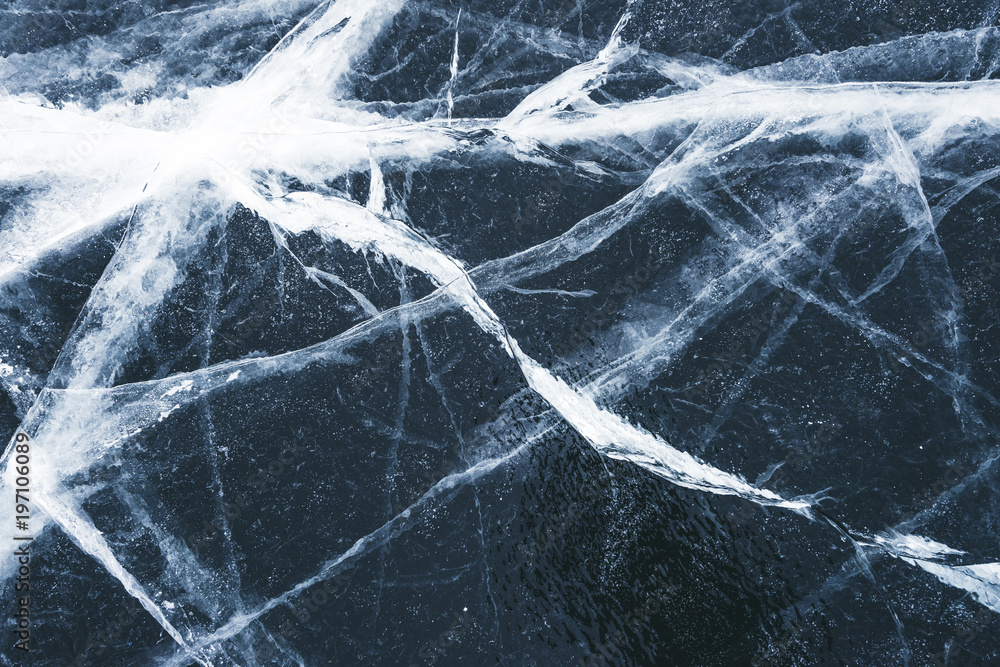 Crack in the ice on a frozen lake covered with snow. Cracked black ice texture background Crack in the ice on a frozen lake covered with snow. Cracked black ice texture background