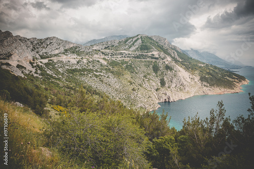 Aerial view on the cliff going down in the adriatic sea with dramatic cloudy sky, Croatia