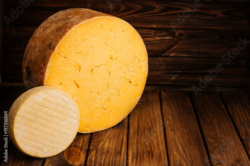 Top View of Farmhouse Yellow Cheese on Wooden Brown Background with Free Space for Text at the Top of the Photo.