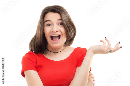 Portrait of a beautiful surprised or very excited young woman wearing red t-shirt showing something in her hand, white background, studio shoot