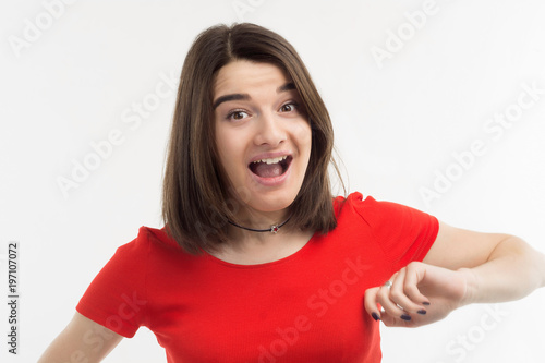 Portrait of a beautiful surprised young woman wearing red t-shirt in a hurry, white background, studio shoot.