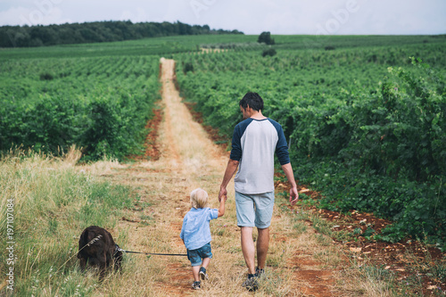 Father and son walking with dog on nature, outdoors.