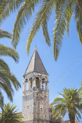 Bell tower of the Saint Dominican convent and church in Trogir, Croatia, surrounded by palm trees © Melanie