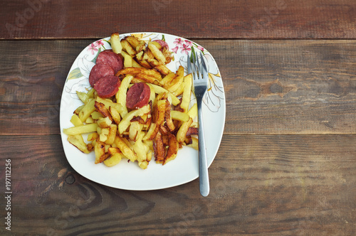The concept of a disturbed diet. Fried potatoes and sausage.