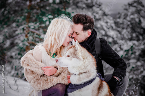 Fantastic couple sitting together with a dog in the mountains