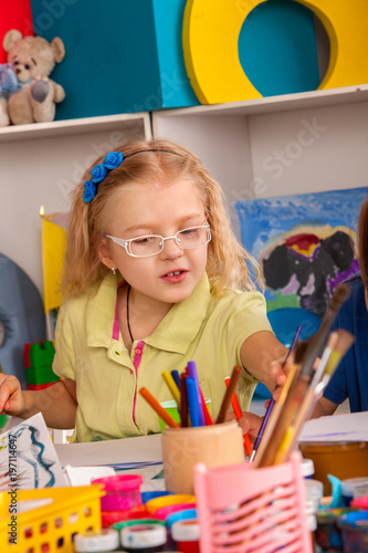 Small students painting in art school class. Child drawing by paints on table. Boy and girls in kindergarten. Best choice of brushes for watercolor painting. Art children's school. photo