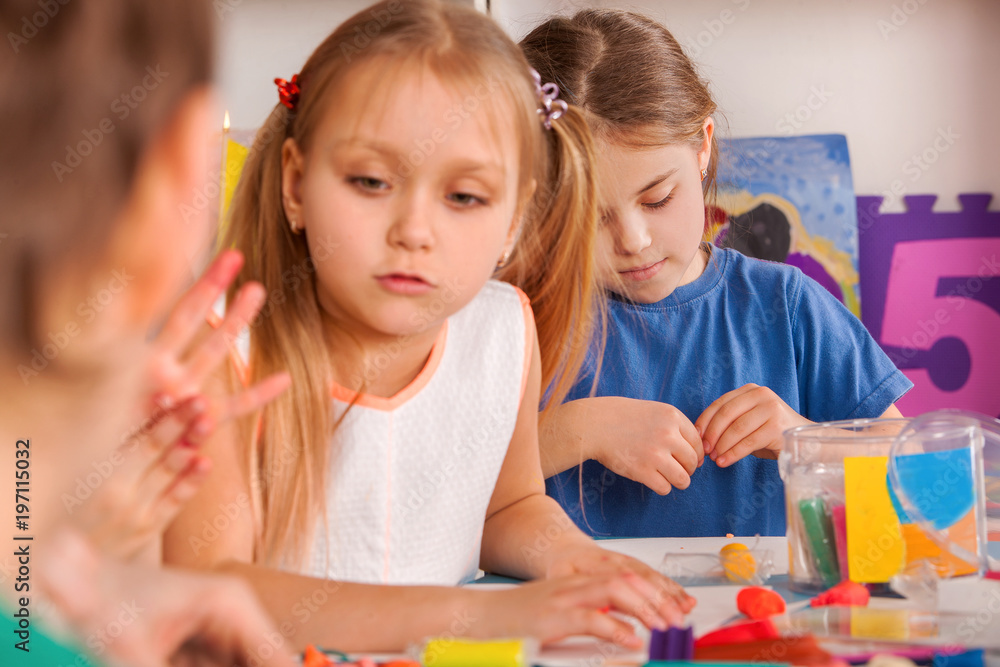 Plasticine modeling clay. Child dough play in school mold from plasticine  in kindergarten. Kids knead modeling clay with hands in preschool.  Preparation for exhibition of crafts made of plasticine. Stock Photo