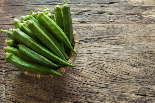 Fotografie raw okra fruit in bamboo basket on old and crack wooden background with copy space