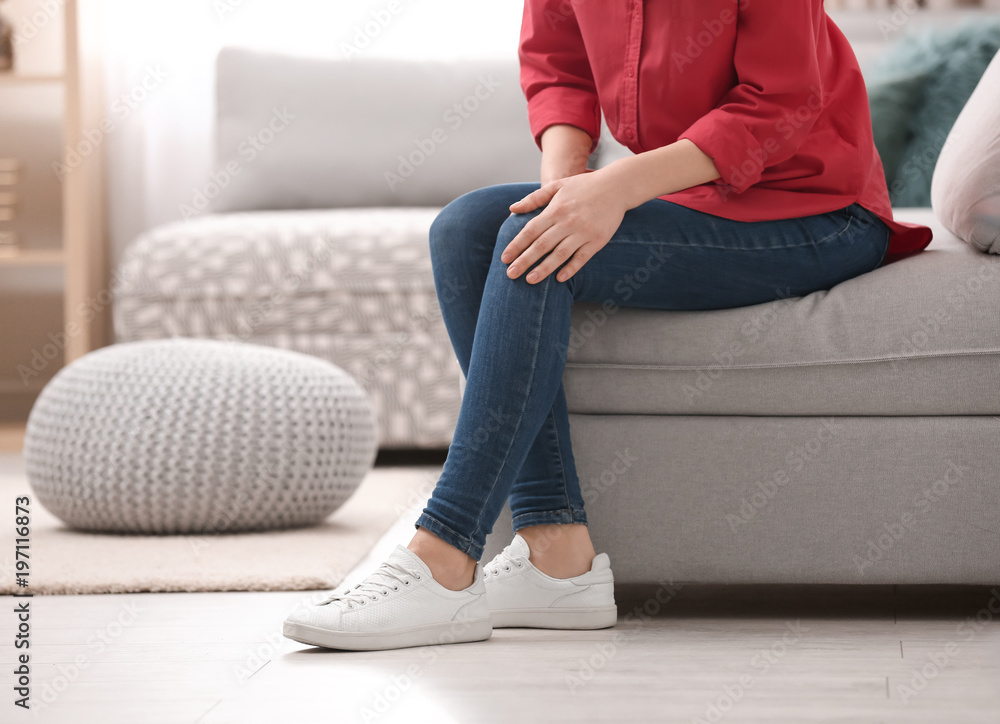 Young woman suffering from knee pain at home Young woman suffering from knee pain at home