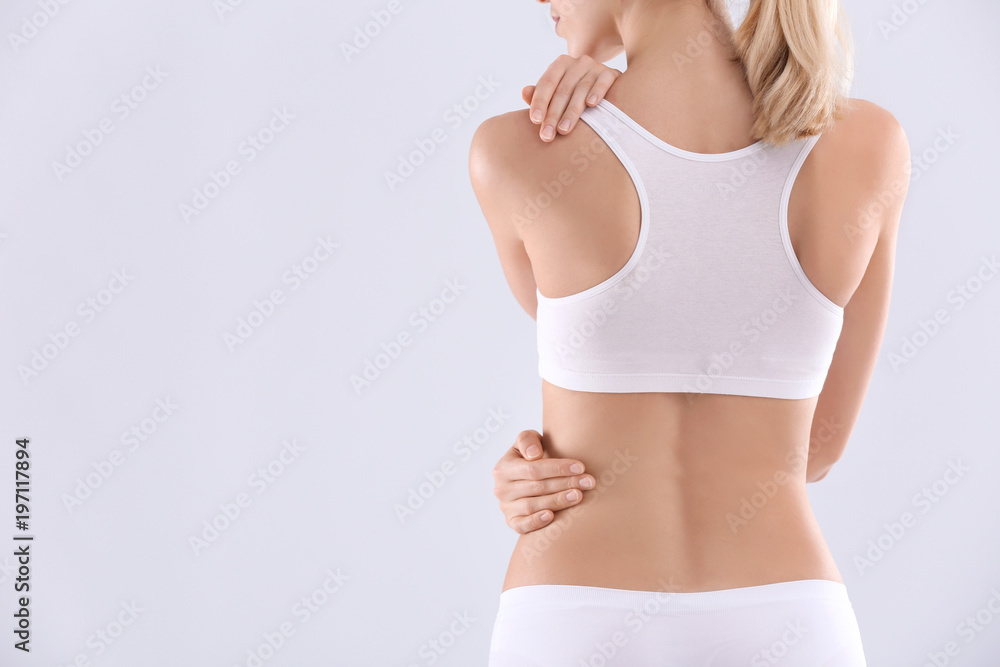 Young woman with beautiful slim body on light background