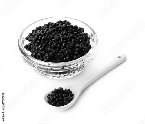 Glass bowl and spoon with black caviar on white background