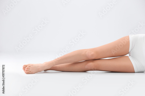 Young woman with beautiful silky body on light background, closeup of legs