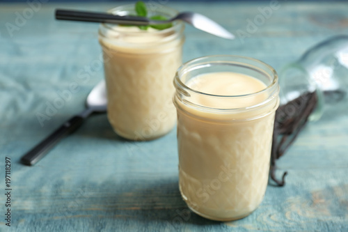 Jar with vanilla pudding on wooden background