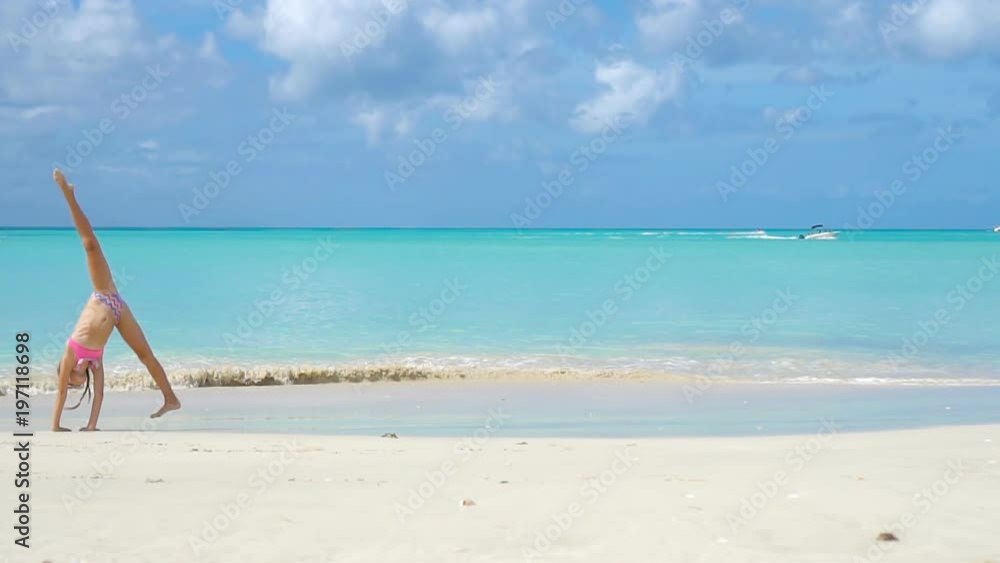 Adorable little girl at beach having a lot of fun in shallow water. SLOW MOTION Adorable little girl at beach having a lot of fun in shallow water. SLOW MOTION