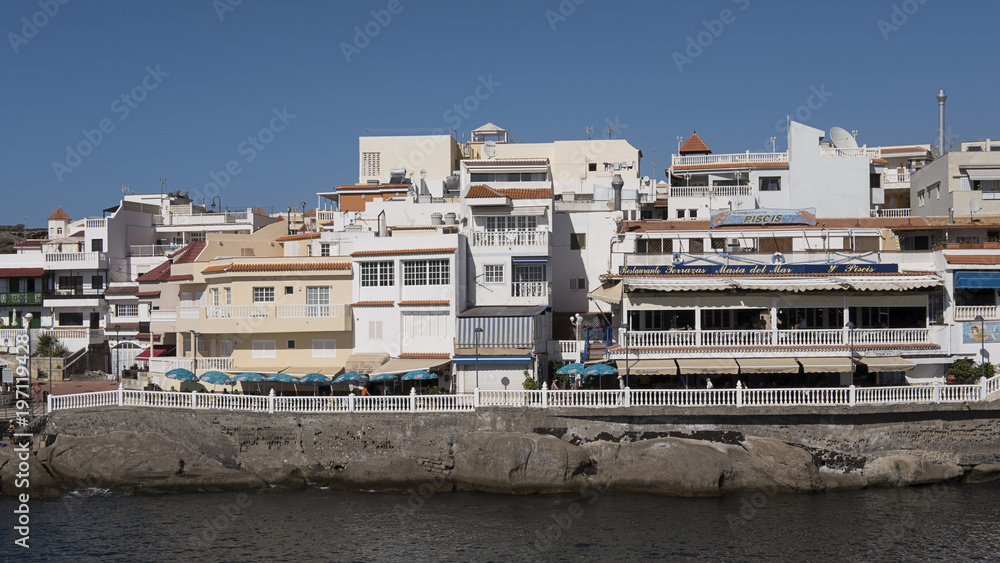 Cluster of houses and fish restaurants in the quaint village of La Caleta situated on the western sunny coast of Tenerife, Canary Islands, Spain