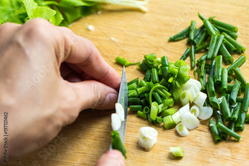 Tableau sur toile Woman hands holding knife chop on green onions.