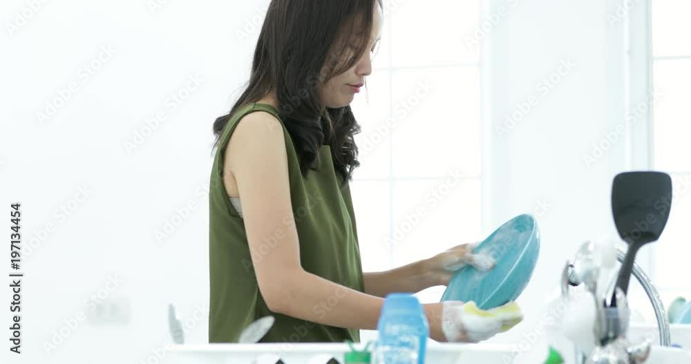 Asian Woman washing plate in kitchen sink Asian Woman washing plate in kitchen sink