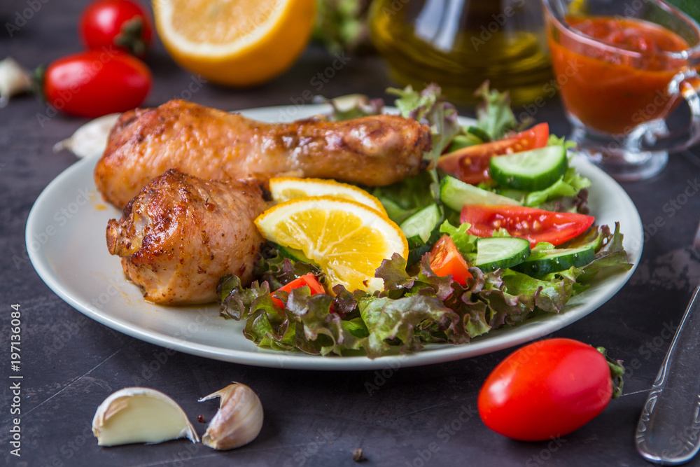 Fried chicken legs and fresh salad on a dark background