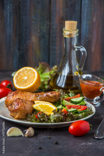 Fried chicken legs and fresh salad on a dark background
