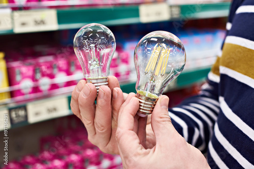 LED and incandescent lamp in hands on store
