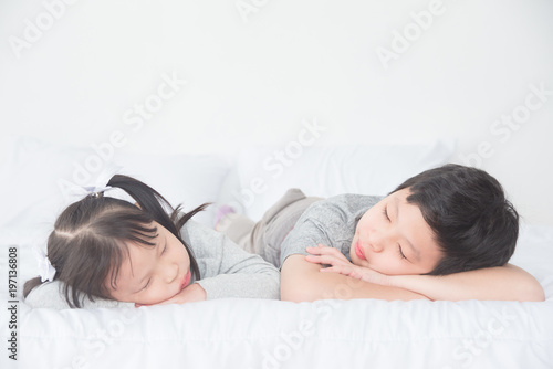Two Asian siblings fall asleep on bed in day time
