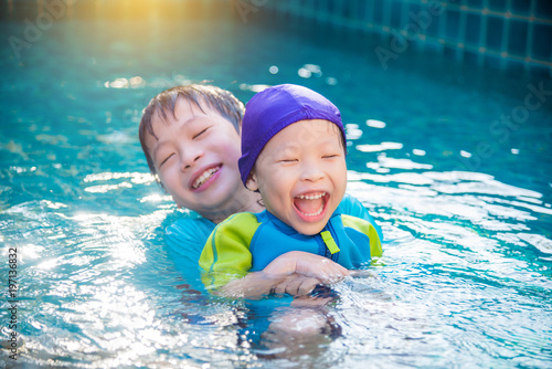 Asian children in swimming suit playing in swimming pool