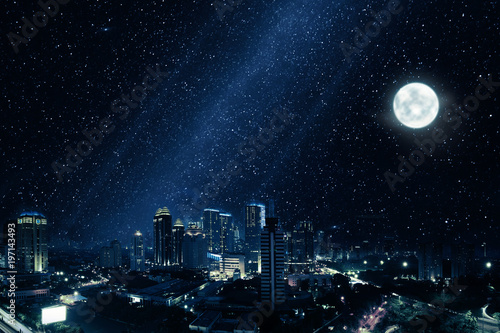 Glowing city with bright moon and many stars in sky