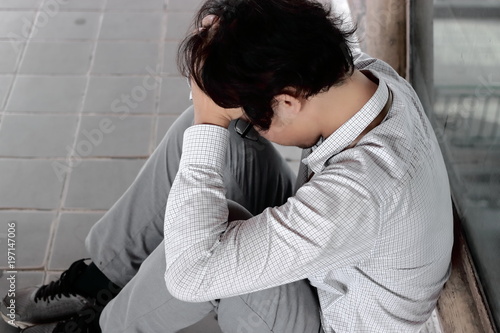 Side view of anxious depressed young Asian business man with hands covering face and feeling disappionted or exhausted with job.