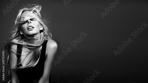 Beautiful young woman with curly blond hair. Fashion studio shot. Black and white image