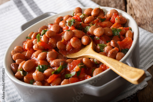 Organic Borlotti beans in tomato sauce with herbs close-up in a bowl. horizontal