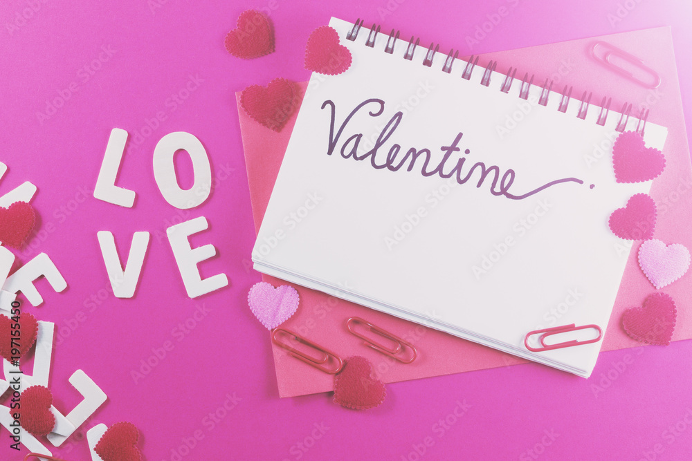 Valentine's day love letter with notebook on pink paper background with copy space.