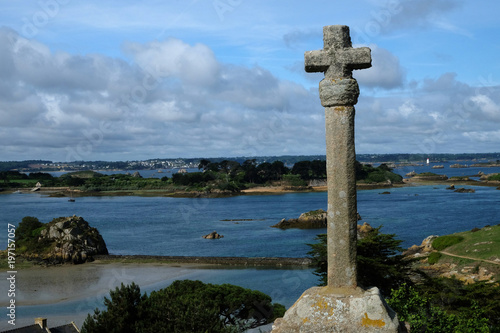 stony historic cross on a blue sky with countryside and the bay © robomelo