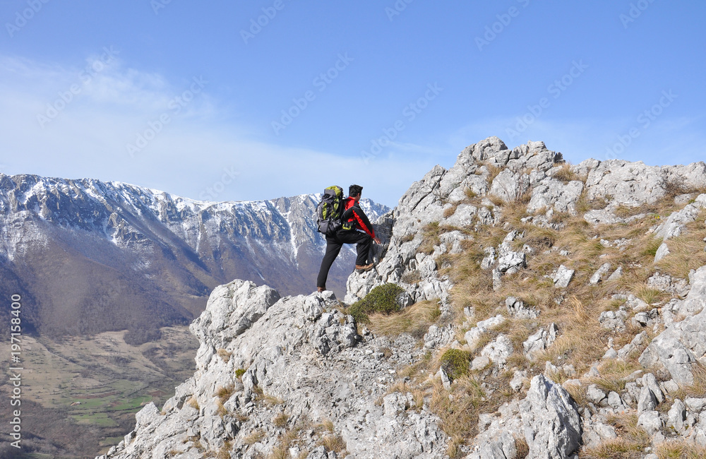 Hiker enjoy in a view on mountain range. Young man high in mountain in spring time.