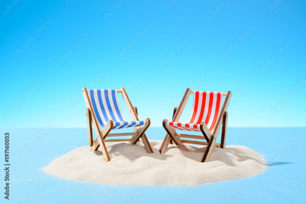 Two sun loungers on a sandy island, copy space