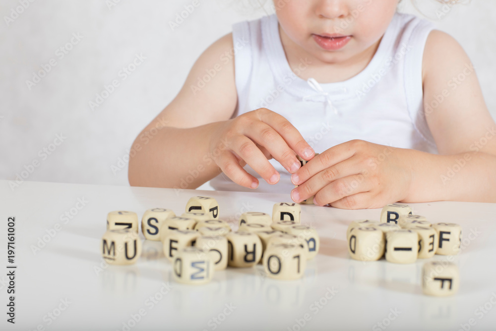 Small girl composes words from letters. Closeup Small girl composes words from letters. Closeup
