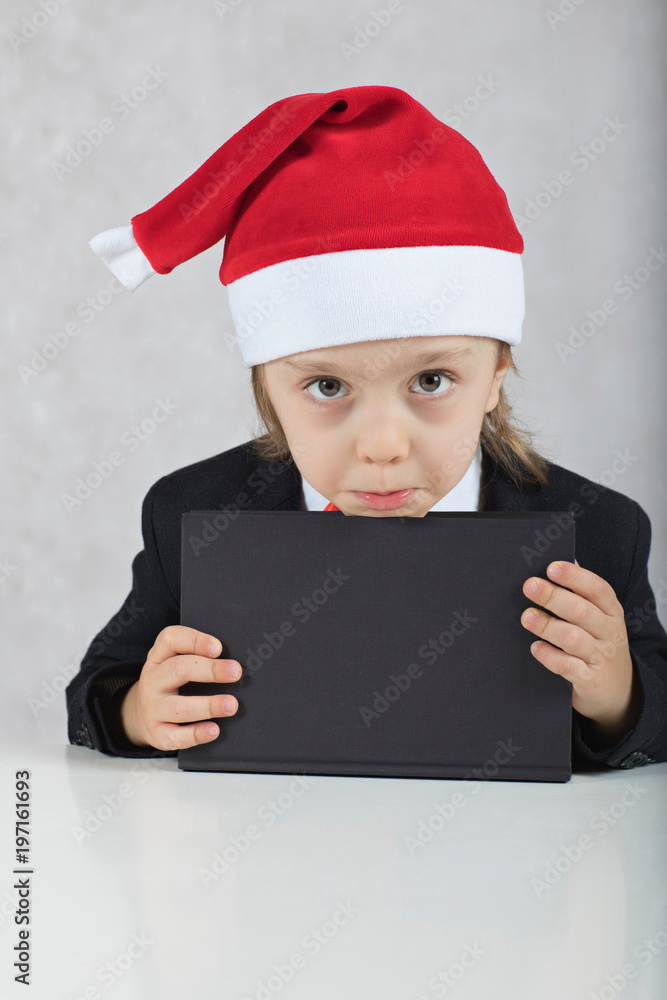 Boy in Santa's hat and black classical jacket. , Boy in Santa's hat and black book. Boy in Santa's hat and black classical jacket. , Boy in Santa's hat and black book.