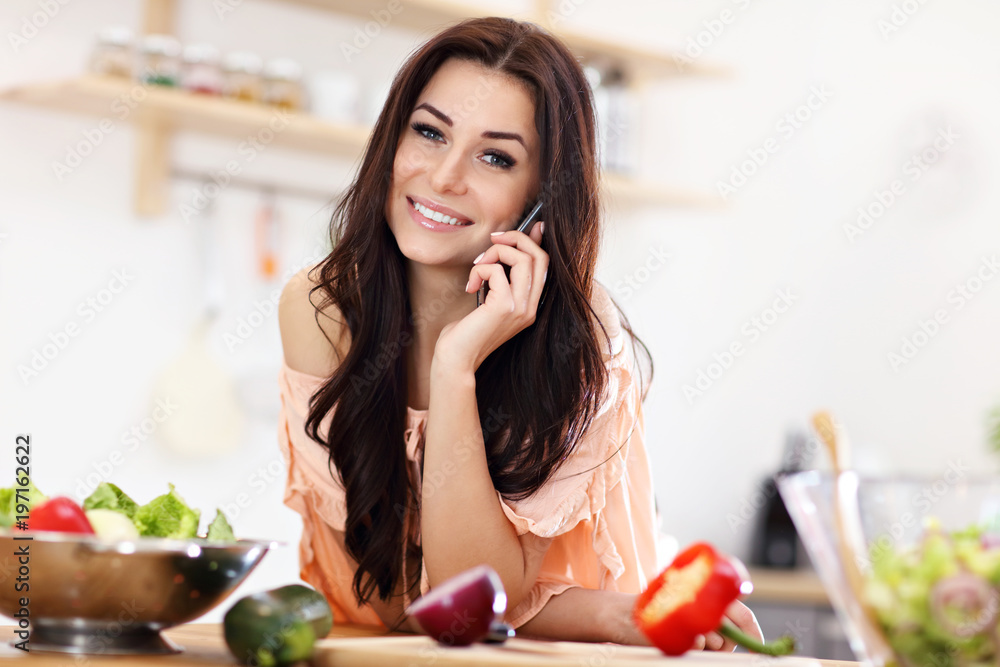 Happy woman preparing salad in modern kitchen