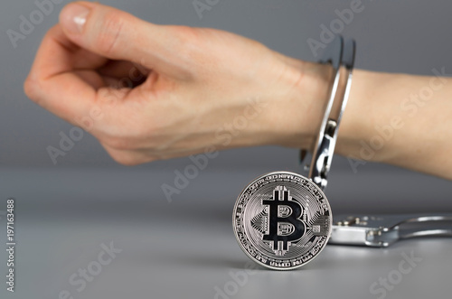 Bitcoin in front of hand in handcuff.