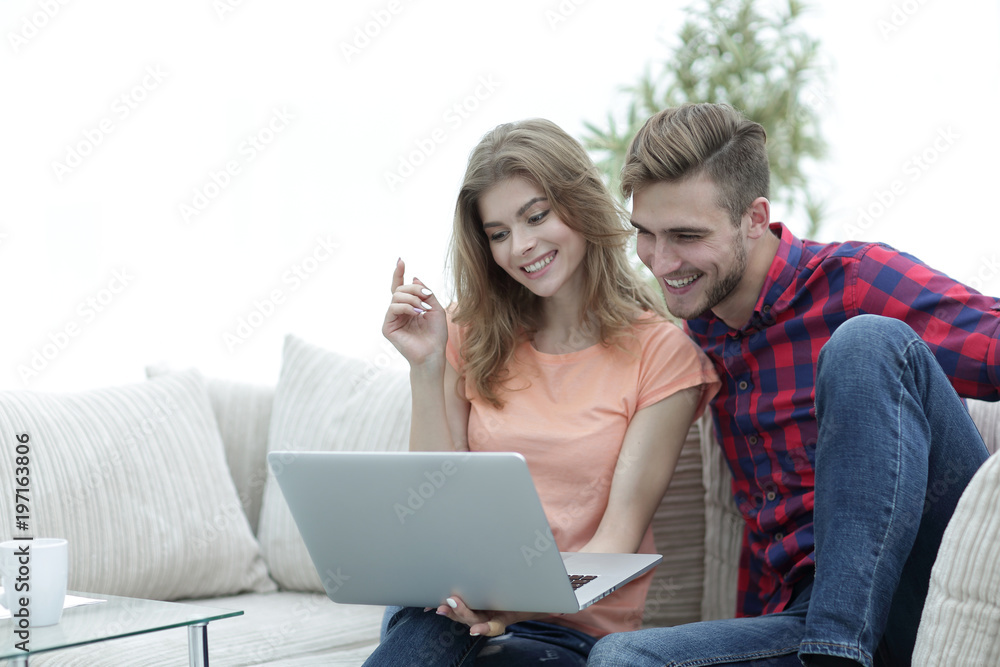 young man with his girlfriend watching a TV show on the laptop sitting in the living room