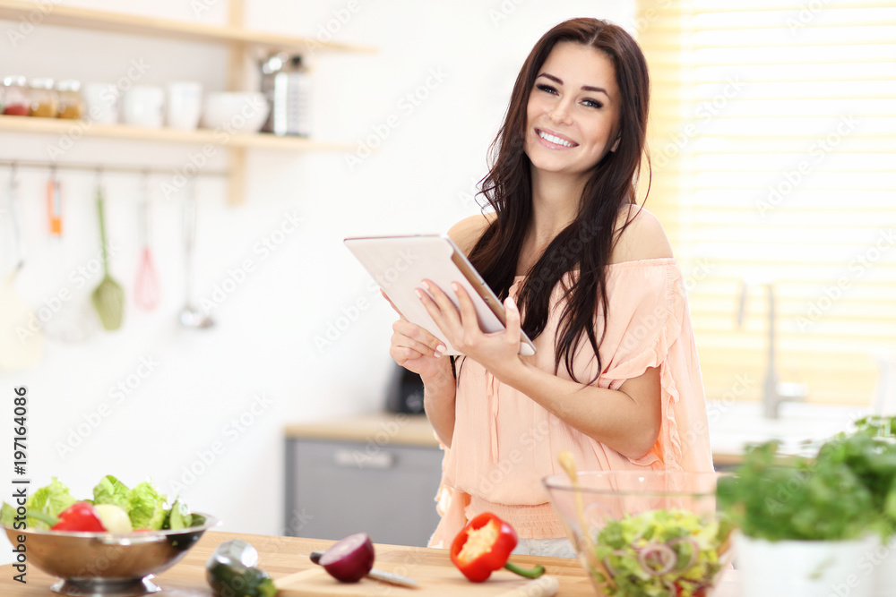 Happy woman preparing salad in modern kitchen and holding tablet Happy woman preparing salad in modern kitchen and holding tablet