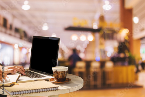 Businessman working with of laptop with blank white screen and coffee in coffee shop like the background.