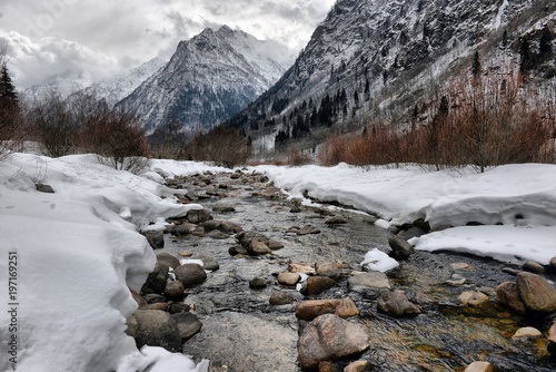 Alpine mountain river in winter on a cloudy day