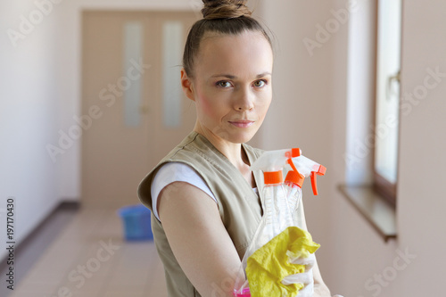 Young cleaning lady is cleaning the corridor.