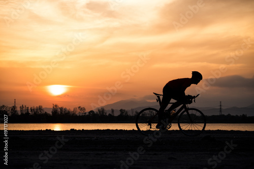 Silhouette a road bike cyclist man cycling in the morning.