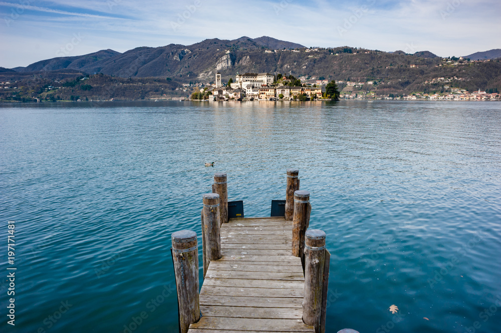 Wooden dock on Lake Orta, opposite the island of San Giulio island with a Benedictine nunnery monastery