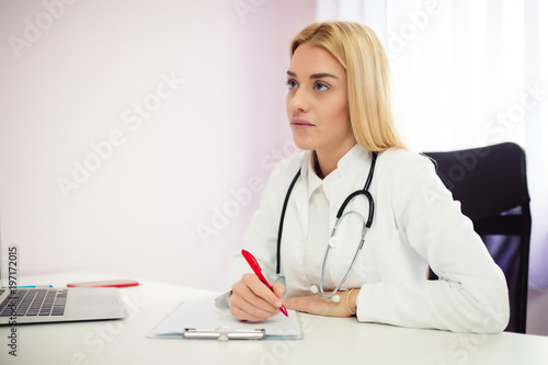 Close up of a female doctor filling up an application form while consulting patient. Medicine and health care concept