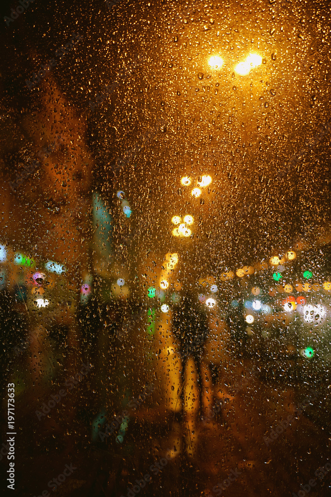 Rain drops on glass surface with bokeh night city lights from lanterns